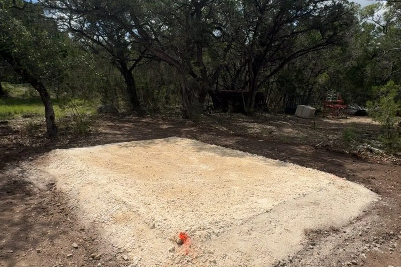 Compacted crushed limestone base pad built under a live oak on a Hill Country property